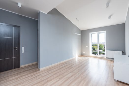 Bright, spacious minimalist room with wooden flooring and large window view.